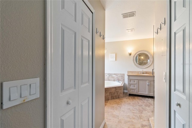 bathroom with vanity, a closet, tile patterned floors, visible vents, and a garden tub