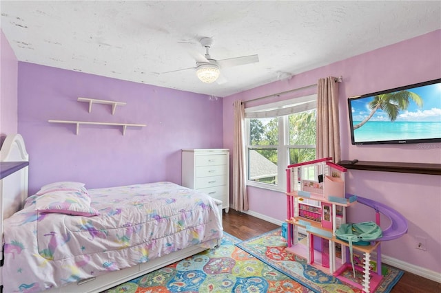 bedroom with a textured ceiling, ceiling fan, wood finished floors, and baseboards