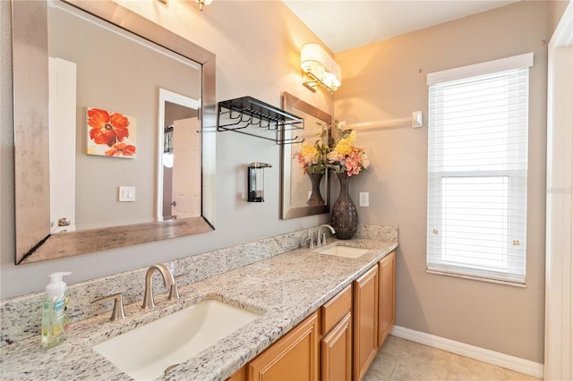 bathroom with double vanity, baseboards, tile patterned flooring, and a sink