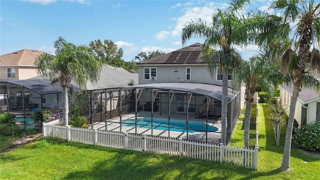back of house with a patio, a fenced in pool, a fenced backyard, a lawn, and solar panels