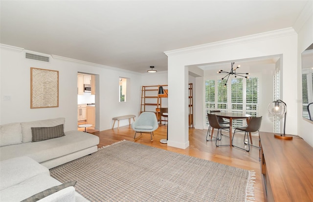 living room featuring plenty of natural light, light wood-style flooring, visible vents, and a chandelier