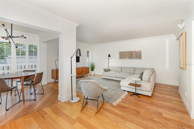 living room featuring light wood-style flooring, baseboards, a notable chandelier, and crown molding