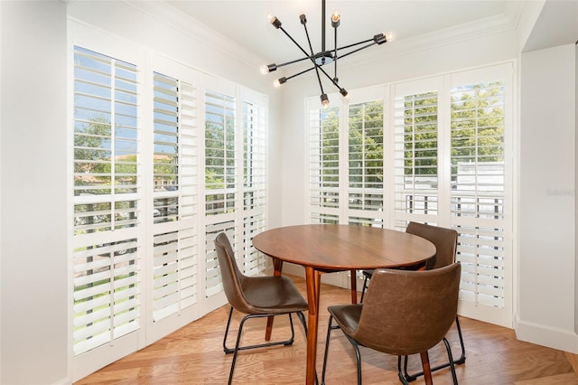dining area with light wood-type flooring, a notable chandelier, ornamental molding, and plenty of natural light