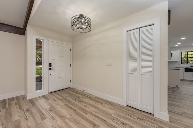 foyer with an inviting chandelier, baseboards, recessed lighting, and light wood-style floors
