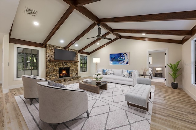 living room featuring vaulted ceiling with beams, light wood-type flooring, ceiling fan, a fireplace, and visible vents