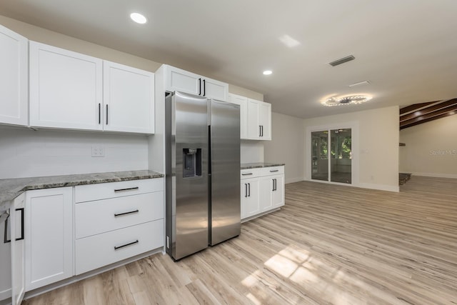 kitchen with white cabinets, visible vents, light wood-style floors, stone counters, and stainless steel refrigerator with ice dispenser
