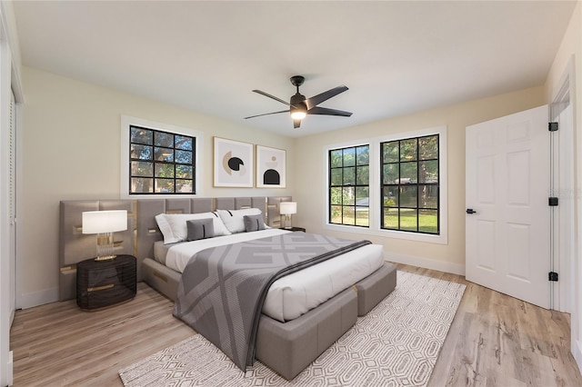 bedroom featuring ceiling fan, baseboards, and light wood-style floors