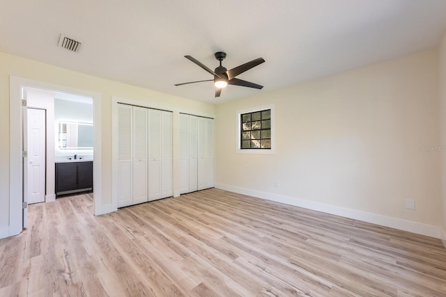 unfurnished bedroom with light wood-type flooring, baseboards, and two closets