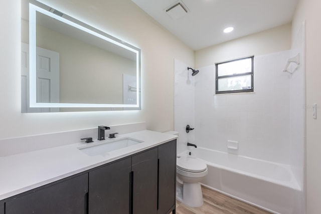 bathroom with toilet, visible vents, wood finished floors, vanity, and shower / tub combination