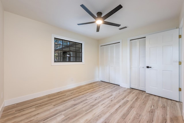 unfurnished bedroom featuring light wood finished floors, baseboards, visible vents, and two closets