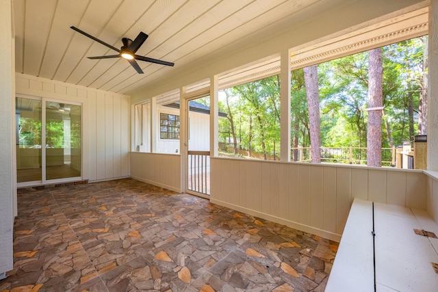 unfurnished sunroom featuring a ceiling fan and a wealth of natural light