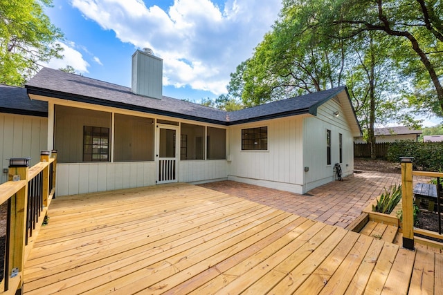 wooden deck featuring a sunroom, fence, and a patio area