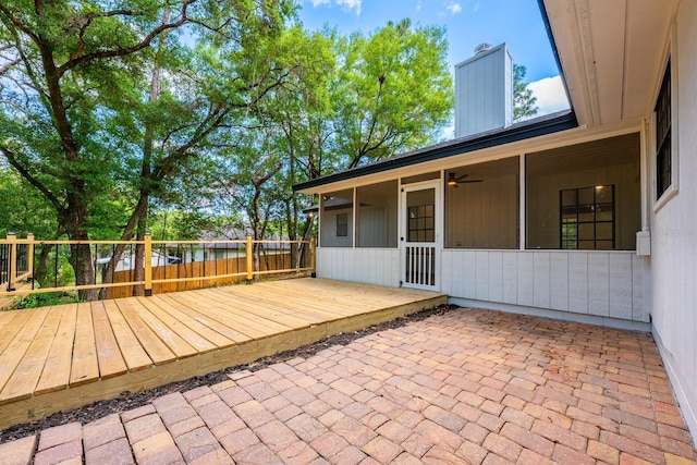 exterior space with a wooden deck, a sunroom, fence, and ceiling fan