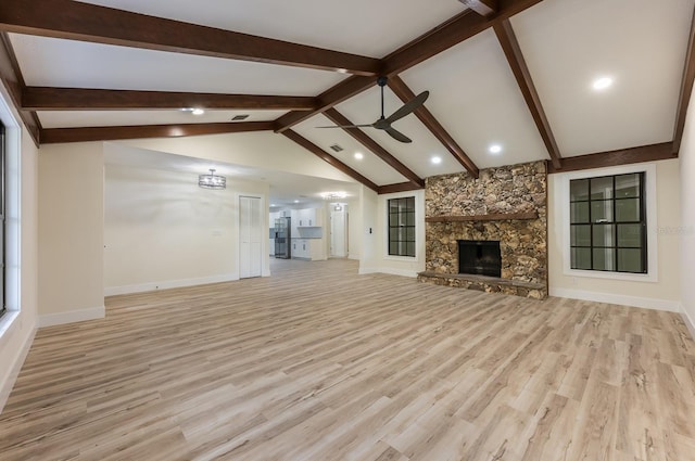 unfurnished living room featuring light wood finished floors, baseboards, lofted ceiling with beams, a fireplace, and ceiling fan