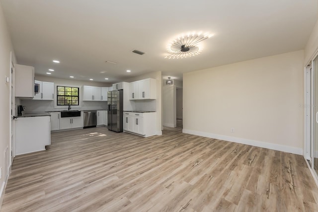 kitchen with stainless steel appliances, visible vents, a sink, light wood-style floors, and open floor plan