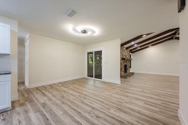 unfurnished living room featuring baseboards, light wood-style flooring, visible vents, and a fireplace