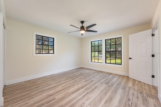 spare room featuring light wood-style flooring, baseboards, and a ceiling fan