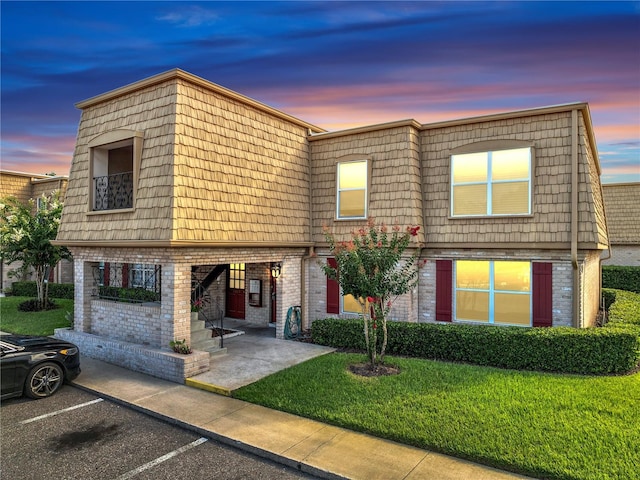 200 Saint Andrews Blvd Unit 2306, Winter Park, FL 32792 - view of front of home with mansard roof, brick siding, a yard, and uncovered parking