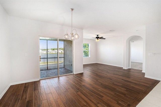 unfurnished room with arched walkways, baseboards, ceiling fan with notable chandelier, and dark wood-style floors