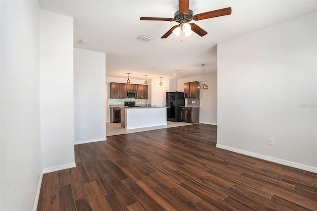 unfurnished living room with baseboards, visible vents, dark wood finished floors, and ceiling fan with notable chandelier