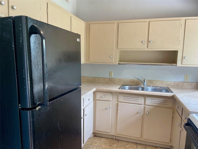 kitchen with open shelves, a sink, cream cabinets, light countertops, and freestanding refrigerator