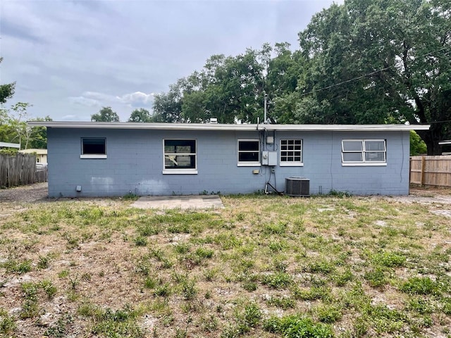 rear view of property with central AC unit, fence, concrete block siding, and a patio area
