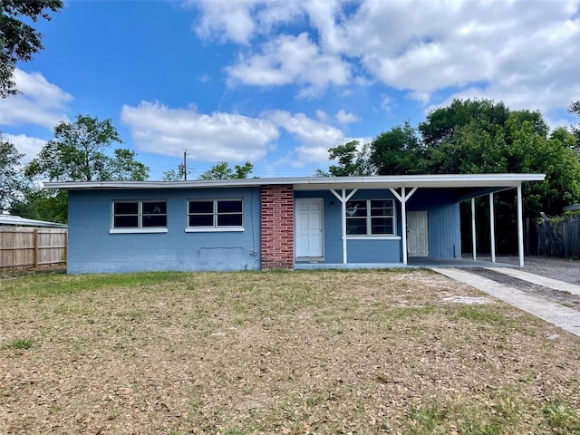 single story home featuring fence, a front lawn, driveway, concrete block siding, and a carport