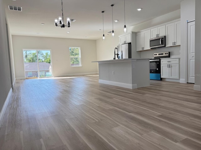 2406 SW 163rd Pl, Ocala, FL 34473 - kitchen with appliances with stainless steel finishes, open floor plan, a chandelier, light wood-style floors, and baseboards