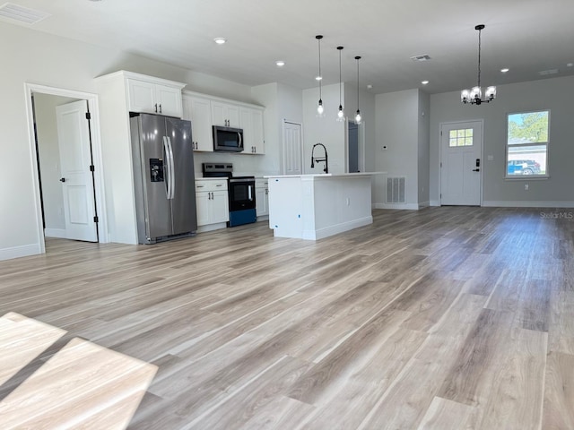 2406 SW 163rd Pl, Ocala, FL 34473 - kitchen with stainless steel appliances, open floor plan, a chandelier, white cabinetry, and light wood finished floors