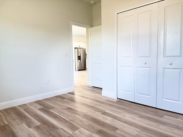 2406 SW 163rd Pl, Ocala, FL 34473 - unfurnished bedroom with stainless steel refrigerator with ice dispenser, light wood-style flooring, a closet, and baseboards