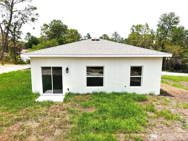 8990 Glenarm Way, Weeki Wachee, FL 34613 - rear view of house featuring roof with shingles, stucco siding, and a lawn