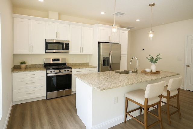 8990 Glenarm Way, Weeki Wachee, FL 34613 - kitchen with appliances with stainless steel finishes, a sink, dark wood-style flooring, a center island with sink, and white cabinets