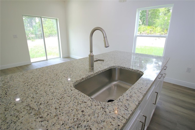 8990 Glenarm Way, Weeki Wachee, FL 34613 - kitchen view of a sink, wood finished floors, light stone counters, baseboards, and white cabinets
