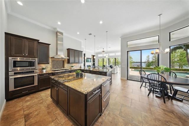 7624 Pointe Venezia Dr, Orlando, FL 32836 - kitchen featuring appliances with stainless steel finishes, wall chimney range hood, dark brown cabinets, open floor plan, and light stone counters