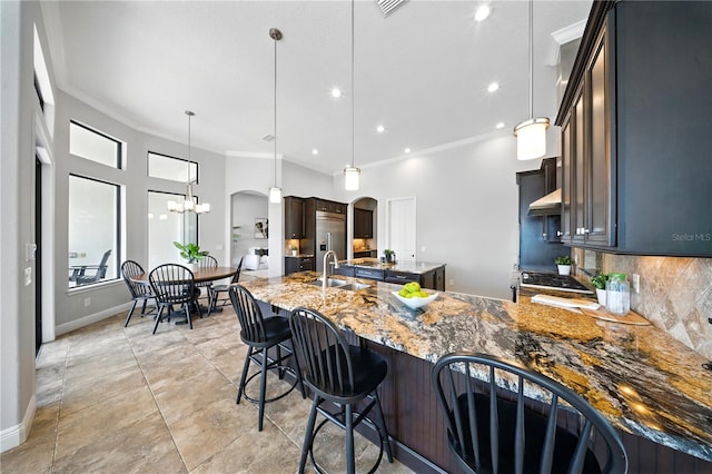 7624 Pointe Venezia Dr, Orlando, FL 32836 - kitchen featuring stone countertops, ornamental molding, a peninsula, backsplash, and pendant lighting