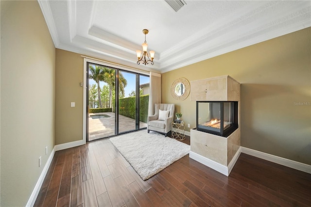 7624 Pointe Venezia Dr, Orlando, FL 32836 - living area with dark wood finished floors, a chandelier, ornamental molding, a multi sided fireplace, and a raised ceiling