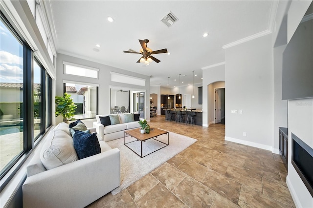 7624 Pointe Venezia Dr, Orlando, FL 32836 - living room with a ceiling fan, a fireplace, ornamental molding, light stone finish flooring, and recessed lighting
