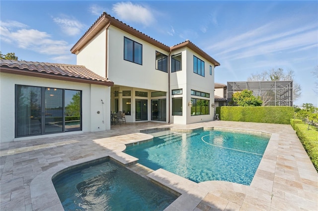 7624 Pointe Venezia Dr, Orlando, FL 32836 - rear view of house with a tiled roof, a patio area, stucco siding, a pool with connected hot tub, and a lanai