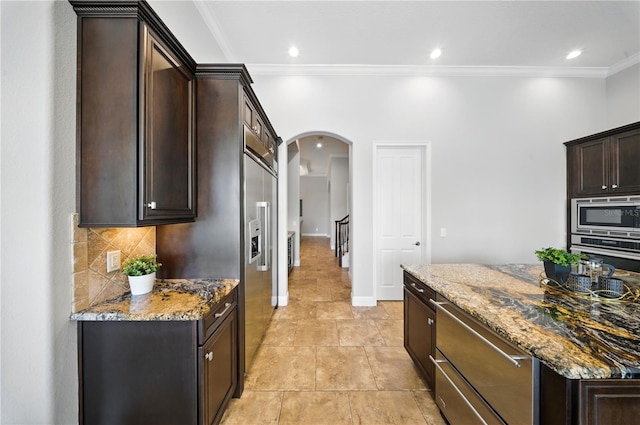 7624 Pointe Venezia Dr, Orlando, FL 32836 - kitchen with arched walkways, appliances with stainless steel finishes, crown molding, dark brown cabinets, and light stone countertops