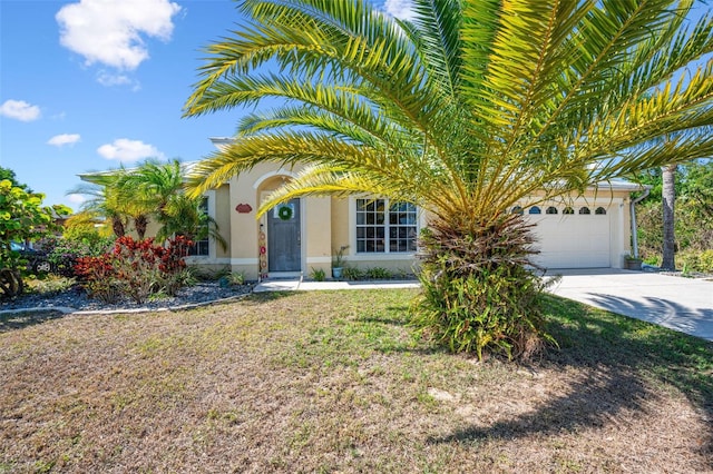view of front of property featuring a garage, driveway, a front yard, and stucco siding