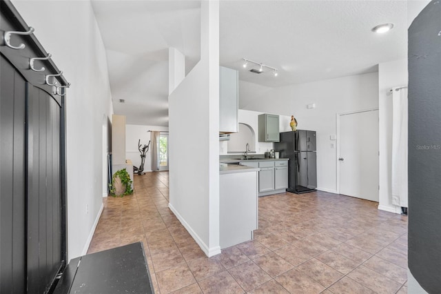 kitchen featuring light tile patterned floors, a sink, light countertops, and freestanding refrigerator