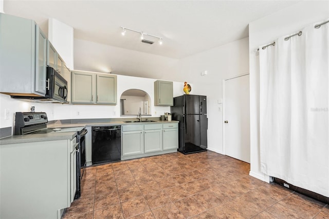 kitchen featuring a sink, black appliances, arched walkways, rail lighting, and lofted ceiling