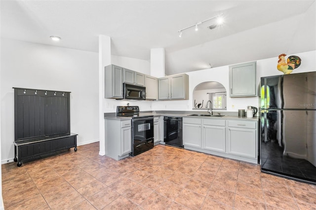 kitchen featuring a sink, black appliances, arched walkways, rail lighting, and lofted ceiling
