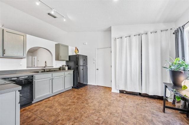 kitchen featuring a sink, visible vents, lofted ceiling, rail lighting, and black appliances