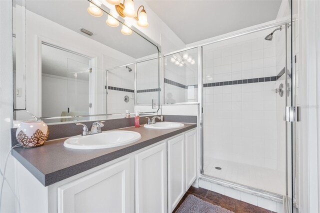 full bath with visible vents, a sink, double vanity, and a stall shower