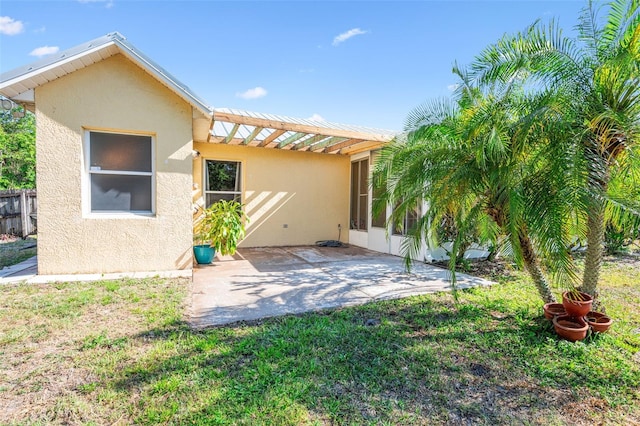 back of property featuring a yard, a patio, stucco siding, and fence
