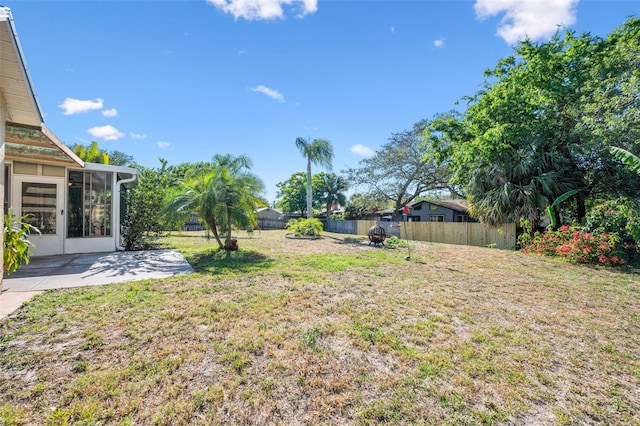 view of yard with a fenced backyard, a sunroom, and a patio area