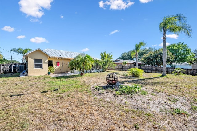 view of yard with a fenced backyard and a fire pit