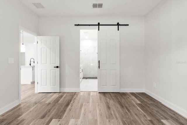 3851 W Wilburton Dr, Citrus Springs, FL 34433 - unfurnished bedroom with a barn door, visible vents, wood finished floors, and baseboards