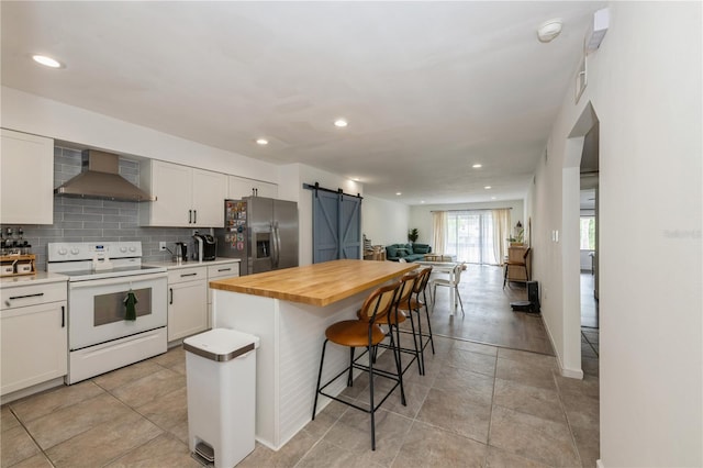 kitchen with wall chimney range hood, a kitchen breakfast bar, white range with electric stovetop, a barn door, and stainless steel fridge with ice dispenser